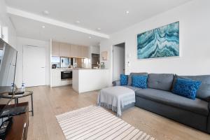 a living room with a couch and a kitchen at Melbourne Docklands Riverside Views in Melbourne