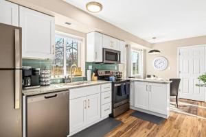 uma cozinha com armários brancos e electrodomésticos de aço inoxidável em New Cozy Lower Flat in Roseville em Roseville