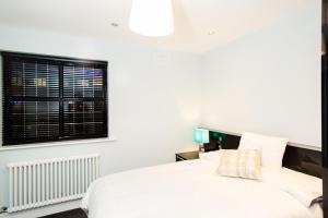 1 dormitorio con cama blanca y ventana en Luxury Townhouse, en Dublín