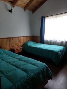 1 dormitorio con 2 camas verdes y ventana en Cancel en Pucón