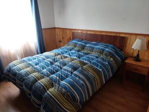 a bed in a bedroom with a blue comforter at Cancel in Pucón