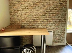 a kitchen with a brick wall and a table and stools at GWR Dickson's B&B in Wick