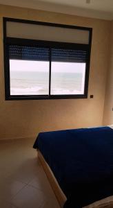 een slaapkamer met een bed en een groot raam bij Amouage résidence in Sidi Ifni