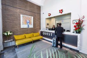 a man with a suitcase standing at a guest counter at Quest Invercargill Serviced Apartments in Invercargill