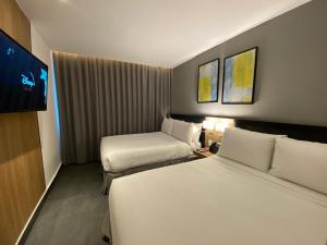 a hotel room with two beds and a flat screen tv at B's Suites Mérida in Mérida