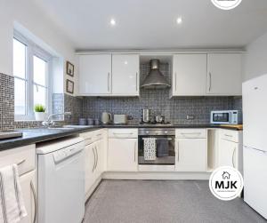 a kitchen with white cabinets and a stove top oven at The Westbourne Short-Stay in Ince-in-Makerfield