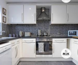 cocina con armarios blancos y fogones en The Westbourne Short-Stay en Ince-in-Makerfield