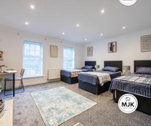 1 dormitorio con 3 camas, escritorio y 2 ventanas en The Westbourne Short-Stay, en Ince-in-Makerfield