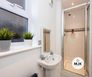 uma casa de banho com um lavatório e um chuveiro em The Westbourne Short-Stay em Ince-in-Makerfield