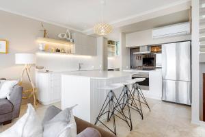 a kitchen with white cabinets and bar stools at Unit 9 Fantastic Holiday Apartment in Sunshine Beach Stunning Views Opposite Beach Access in Sunshine Beach