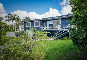 ein blaues Haus mit einem Balkon und einem Hof in der Unterkunft The Sunshine Shack - Boutique Holiday Home in Sunshine Beach