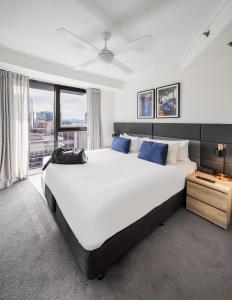 a bedroom with a large white bed with blue pillows at Oaks Brisbane on Felix Suites in Brisbane