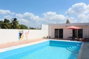 a swimming pool next to a white wall and a house at Casa Rojas, a una calle de la playa! in Progreso