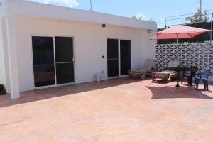 a patio with a table and an umbrella at Casa Rojas, a una calle de la playa! in Progreso
