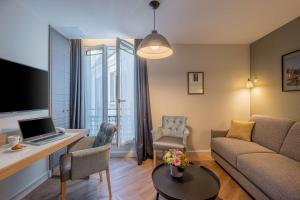a living room with a couch and a desk with a laptop at Hotel Litteraire Le Swann, BW Premier Collection in Paris