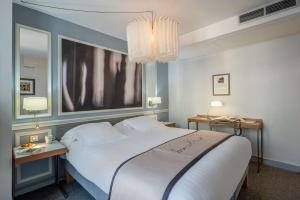 a bedroom with a large white bed and a chandelier at Hotel Litteraire Le Swann, BW Premier Collection in Paris