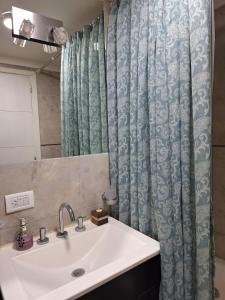 a bathroom with a sink and a shower curtain at Edificio Juana del Mar in Mar del Plata