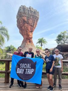a group of people holding asocial day trip flag in front of thepool at Social Hostel Café e Bar in Curitiba