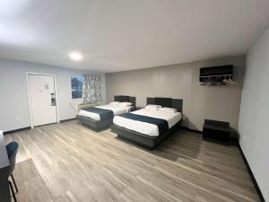 two beds in a room with wooden floors at Motel 6 Williamstown in Williamstown