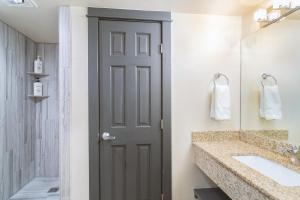 baño con puerta, lavabo y espejo en Mountainside Inn 419-21 Hotel Room en Telluride