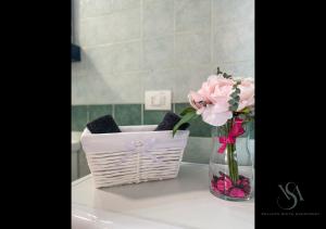 a basket of flowers and a vase with pink flowers at Velluto Suite Apartment in Calderara di Reno