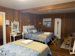 - une chambre avec 2 lits, une table et un bureau dans l'établissement Gite de la Baie Hatée, à Bic