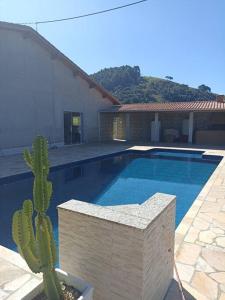 una piscina con un cactus al lado de una casa en Lindo Sítio, Itapeva MG a 120km, en Itapeva