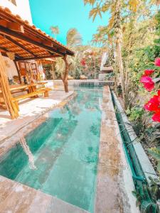 a swimming pool next to a house with a bench at Pousada Fortal Preá in Prea