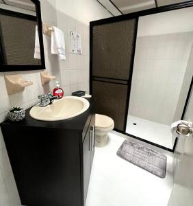 uma casa de banho com um lavatório, um WC e um chuveiro em Cómodo apartamento en la Villa Olímpica de Pereira em Pereira