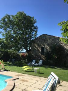 a yard with chairs and a pool and a building at Chez Janie Hirst in Sauzet