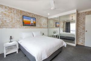 a bedroom with a white bed and a brick wall at Coast Inn Motel in Ballina