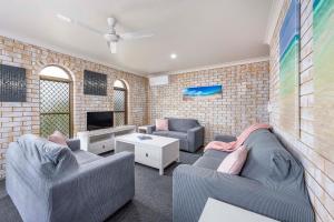 a living room with two couches and a tv at Coast Inn Motel in Ballina