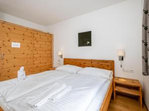 sypialnia z dużym białym łóżkiem z drewnianym zagłówkiem w obiekcie Panorama Top 2 w mieście Mauterndorf