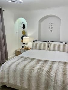 a white bedroom with a large bed with a comforter at Little Venice Garden Apartment in London