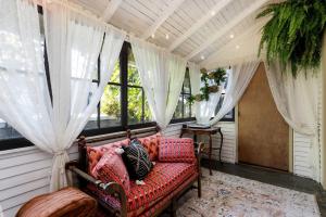 einen Wintergarten mit einem roten Sofa in einem Zimmer mit Fenstern in der Unterkunft The Betty - A 1920s Vintage Bungalow in Portland