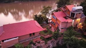 une vue de tête sur une maison avec des toits rouges à côté d'une rivière dans l'établissement Green Bamboo Lodge Resort, à Cat Tien
