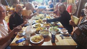 een groep mensen die rond een tafel eten bij Green Bamboo Lodge Resort in Cat Tien