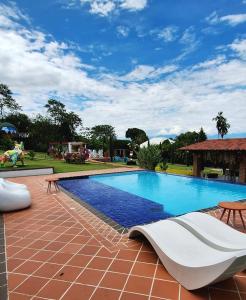 uma grande piscina com uma cama branca e mesas em NG Glamping a 20 min de Neiva em Neiva