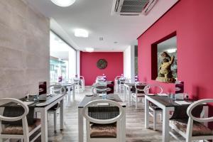 a restaurant with pink walls and white tables and chairs at Barceló Teguise Beach - Adults Only in Costa Teguise