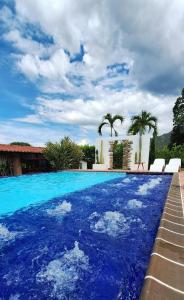 a large swimming pool with blue water in front of a house at NG Glamping a 20 min de Neiva in Neiva