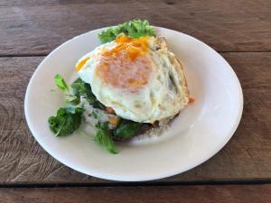 une assiette blanche avec un œuf au-dessus d'une salade dans l'établissement The Last Point Koh Takiev, à Koh Ta Kiev