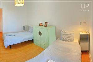 a bedroom with two beds and a dresser with a night stand at SIX by UP Lisbon I Your home away from home in Lisbon