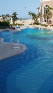 ein Pool mit blauem Wasser neben einem Strand in der Unterkunft royal beach resort hurghada in Hurghada