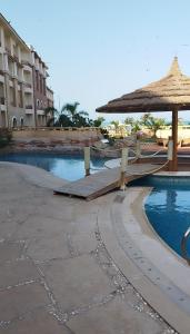 a resort with a pool with a umbrella and a building at royal beach resort hurghada in Hurghada