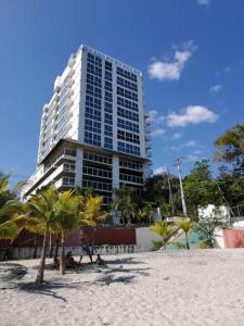 a tall building with palm trees in front of a beach at Ph Ibiza Playa Corona in La Chumicosa