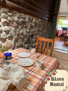una mesa con platos y tazas y una pared de piedra en Hostal Klaus en Pucón