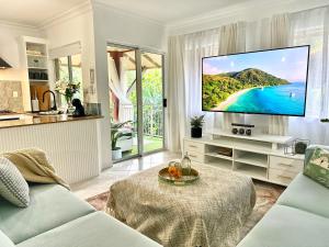 ein Wohnzimmer mit einem Flachbild-TV an der Wand in der Unterkunft Luxury 2 Bedroom apartment, Treetop views, Resort with 4 swimming pools in Cairns North