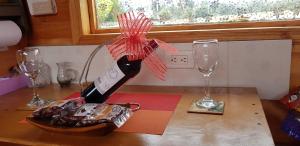 una botella de vino en una mesa con dos copas en Cabaña Los Linos, en Guasca