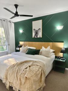 a bedroom with a large bed with a green wall at Luxury tropical 2bedroom apartment in resort 4 swimming pools in Cairns North