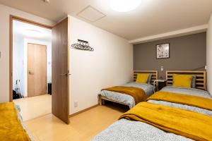2 camas en una habitación con mantas amarillas en Furinkyo・楓林居 7号館, en Osaka